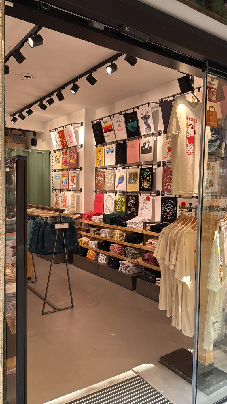 Interior de una tienda terminada, con iluminación en raíles, expositores de pared y mesas de producto