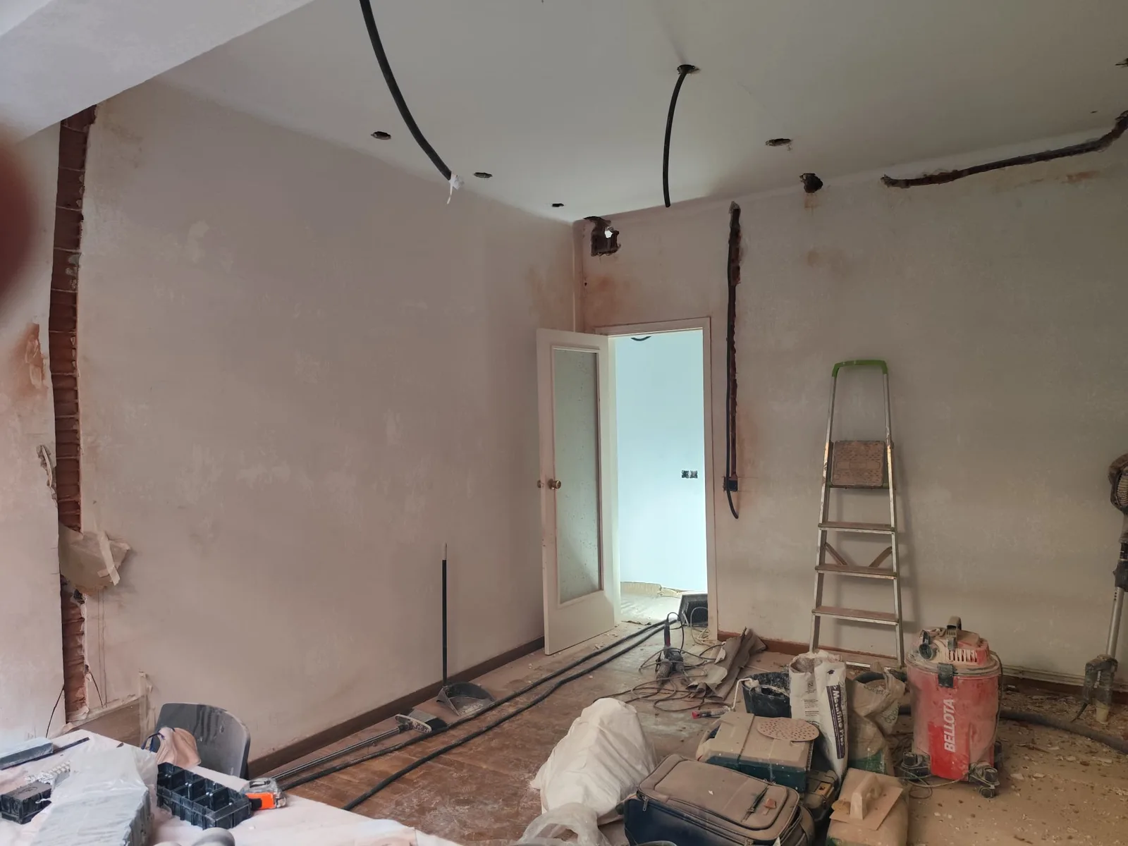 Estancia en obra con el cableado nuevo pasado por el techo y las rozas abiertas en las paredes