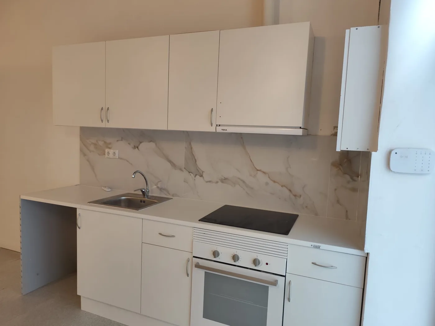 Cocina lineal acabada con frente imitación mármol en la reforma de un local en l’Eixample, Barcelona