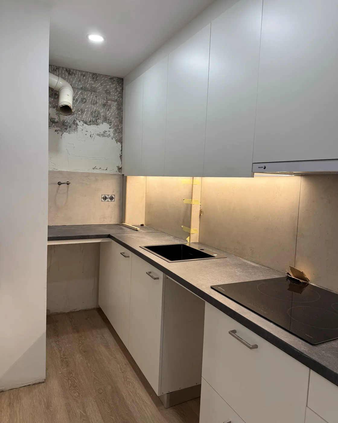 Cocina en L terminada con iluminación bajo los muebles altos, reforma de Obrescat en Sants-Montjuïc, Barcelona