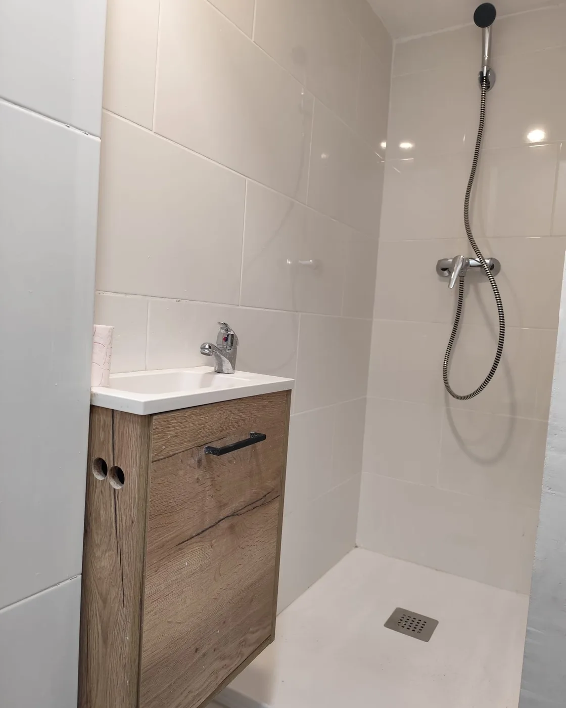 Baño con plato de ducha de obra y mueble de madera terminado por Obrescat en l’Eixample, Barcelona