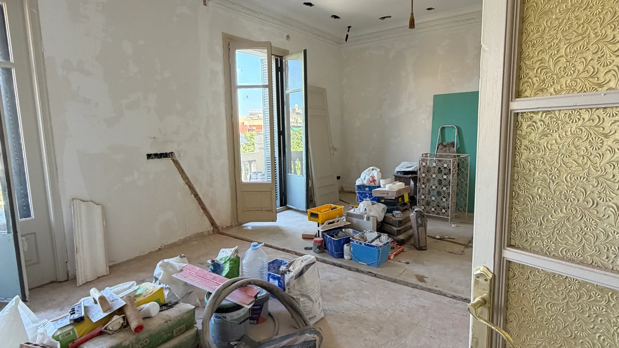 Habitació en obra amb la balconera oberta i el material aplegat, reforma integral a Barcelona