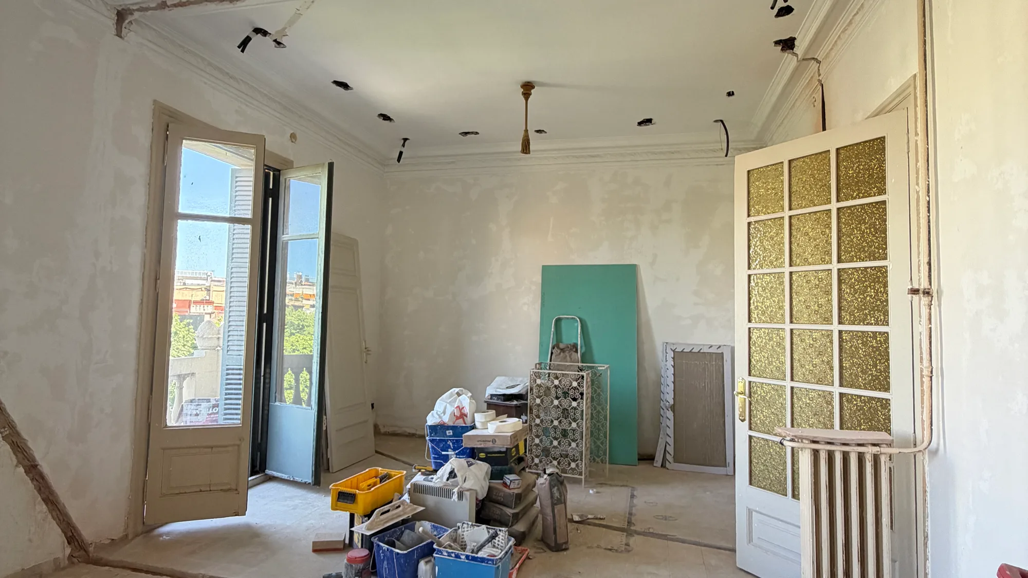 Sala de sostres alts amb la balconera oberta durant una reforma integral a Barcelona