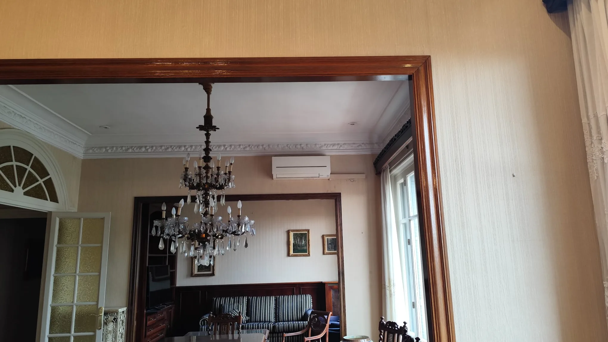 Saló amb motllures de guix i llum d’aranya en un habitatge reformat per Obrescat a Barcelona