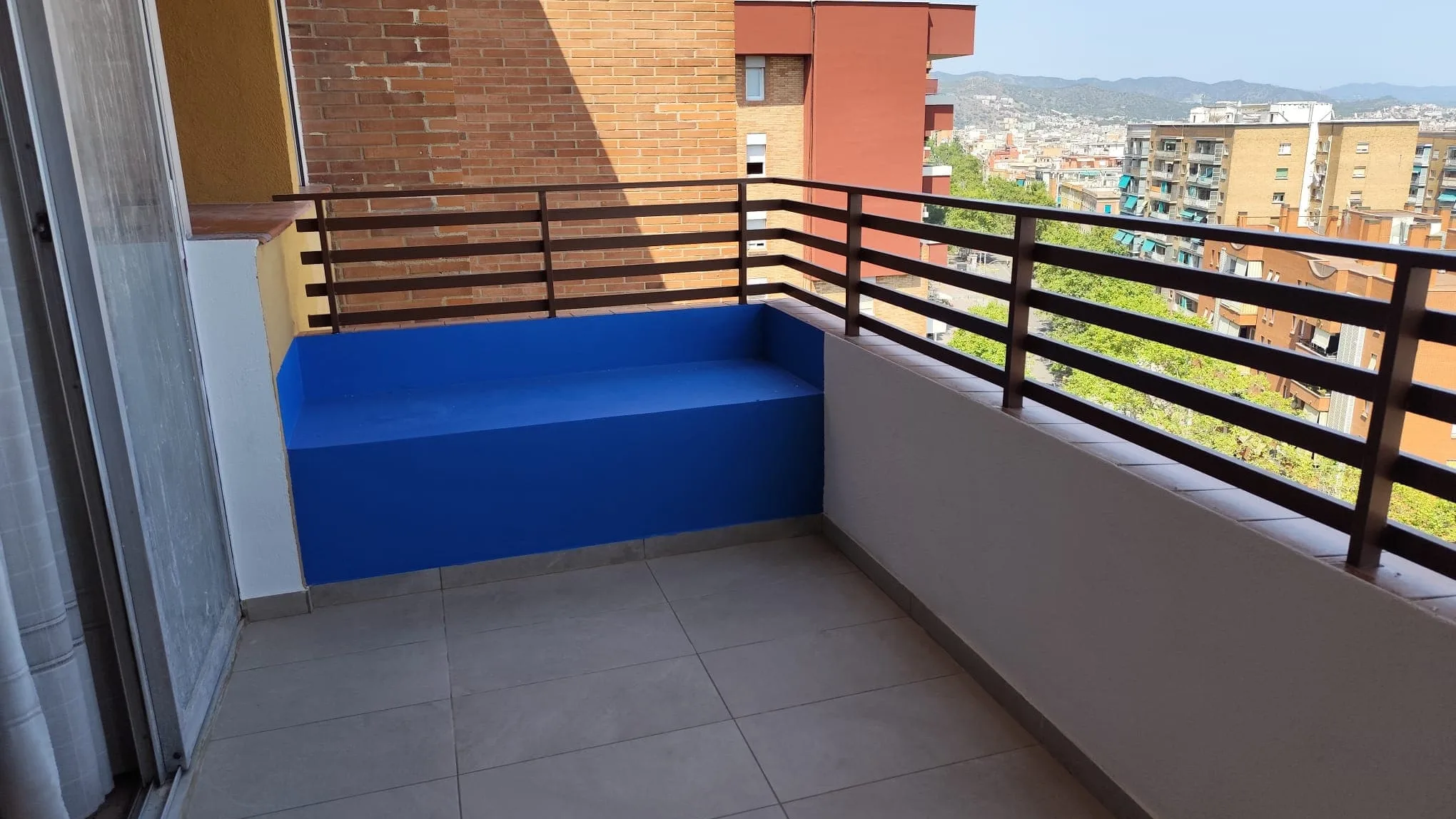 Terrassa reformada amb paviment nou i banc d’obra, amb Barcelona al fons