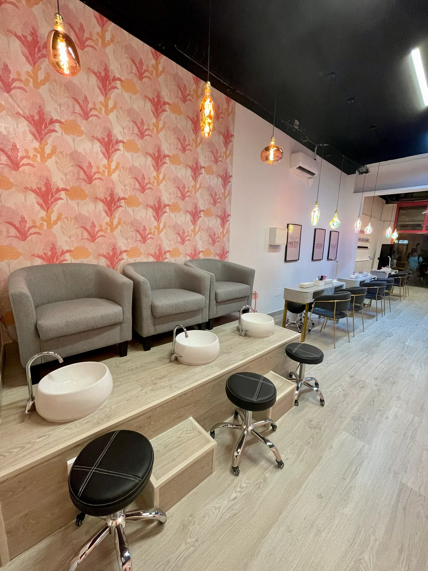 Zona de pedicura de un centro de estética, con butacas, lavapiés y lámparas colgantes
