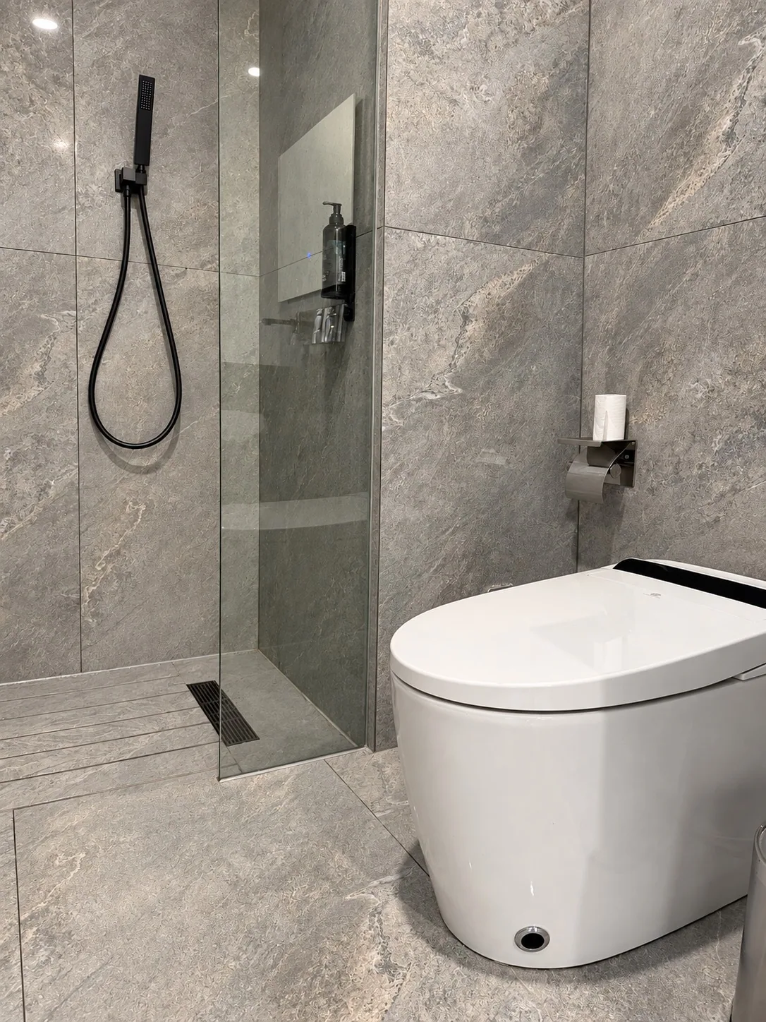 Baño terminado con ducha a ras de suelo, mampara fija y gres de gran formato