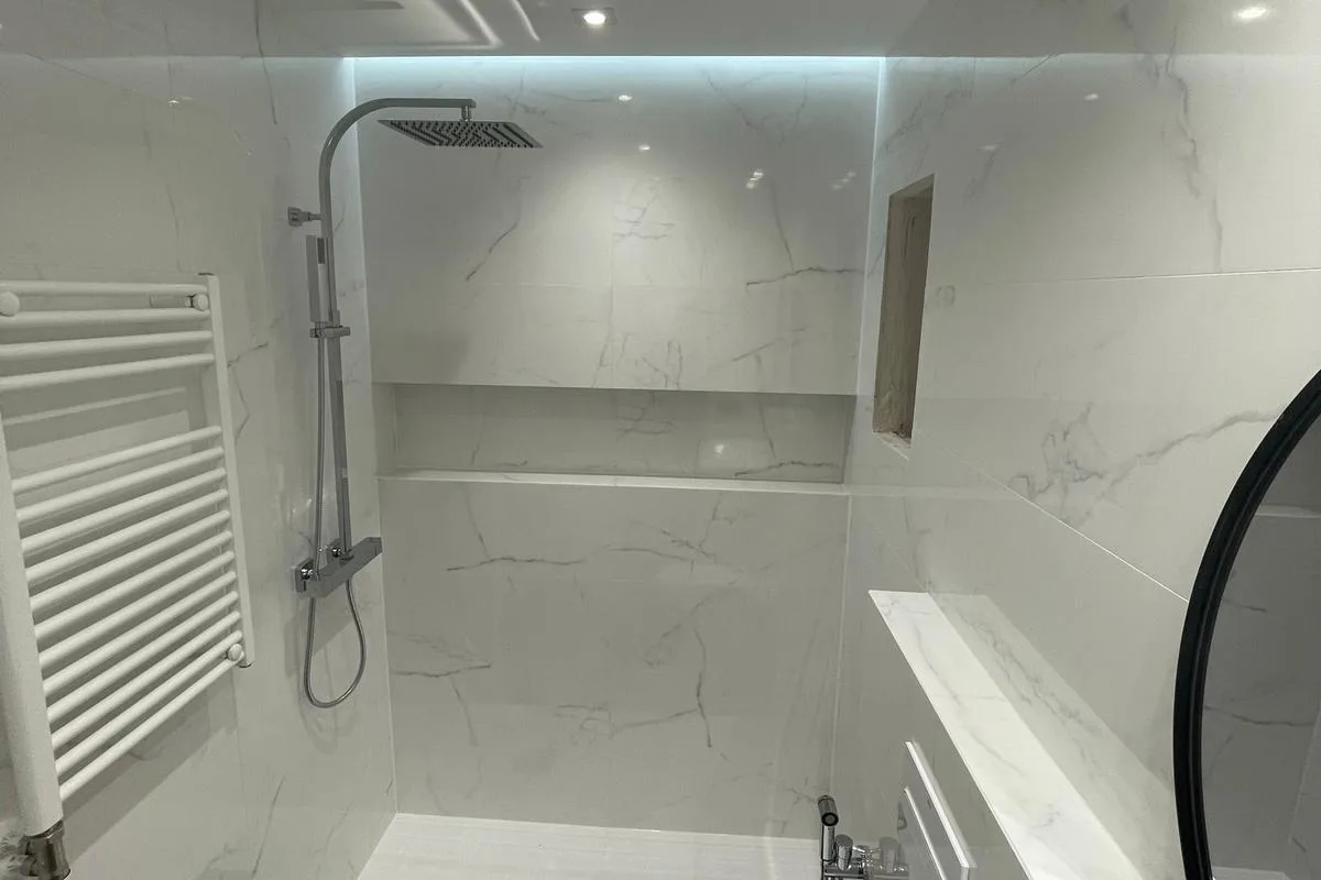 Dutxa acabada amb revestiment de gran format i columna encastada en una reforma de bany a Barcelona