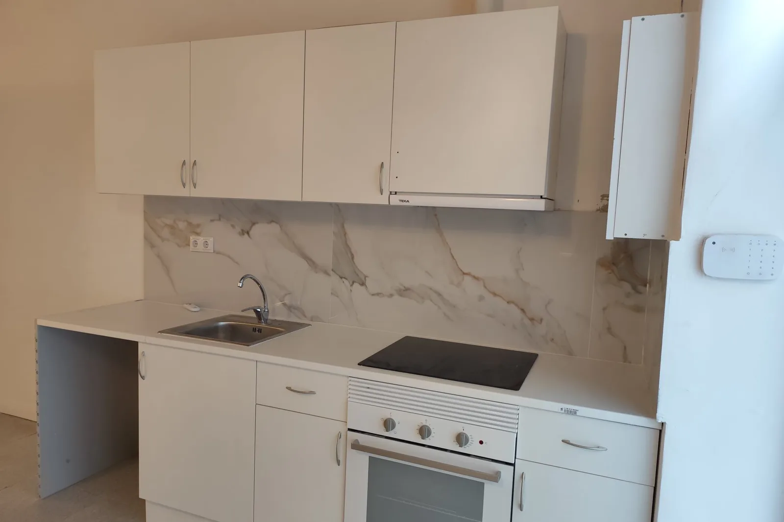 Cuina lineal acabada amb frontal imitació marbre en la reforma d’un local a l’Eixample, Barcelona